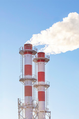 Factory plant smoke stack over blue sky background. Thermal condensing power plant. Energy generation and air environment pollution industrial scene