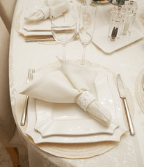Detail of table setting in beige. Elegant and romantic arrangement for dinner. Сandle and glasses.