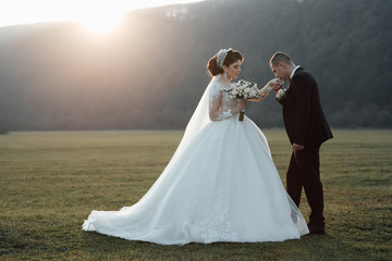 Stylish couple of happy newlyweds walking on their wedding day with bouquet. Couple in love. Sensual portrait of a young wedding couple. Outdoor. 