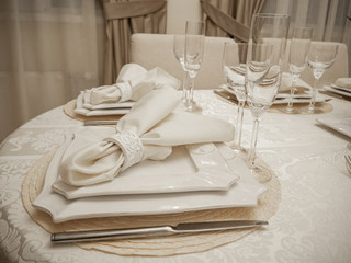 Detail of table setting in beige. Elegant and romantic arrangement for dinner. Сandle and glasses.