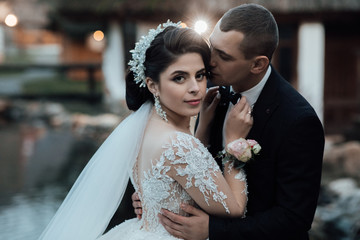 Bride and groom at wedding day walking outdoors. Bridal couple, Happy newlywed woman and man embracing. Loving wedding couple outdoor. Bride and groom