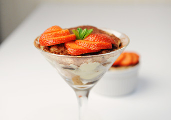 Tiramisu dessert in martini glass. Decorated with strawberry slices and mint. White background, isolated
