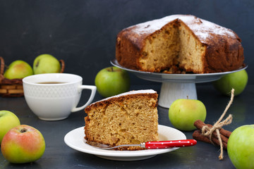Pie with apples, cinnamon and ginger on a dark background, with piece of cake and cup of coffee in the foreground