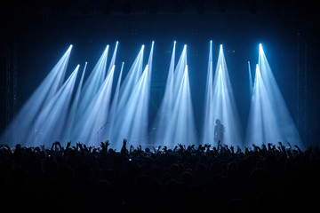 Silhouettes of concert crowd in front of bright stage lights.
