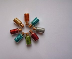circle of small jars with colored sparkles on a white background