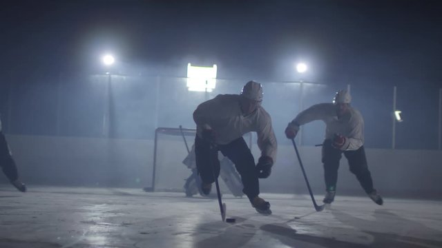 Group of men skating on ice rink while trying to take control of puck while playing hockey together