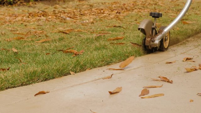 Landscaper edging sidewalk with gas powered blade trimmer. Landscape worker edging residential lawn with grass trimming tool.