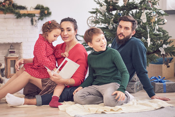 family brother sister and parents sit on the floor open Christmas presents. Family holidays. happy family together