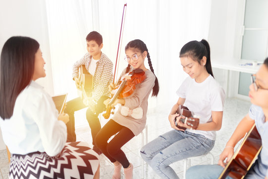 Cute Asian Children Holding Violin On Her Shoulder And Play Violin, She Show Violin Skill And Present Melody And Song To Teacher And Friends, Asian Children Group In Musical Training Time