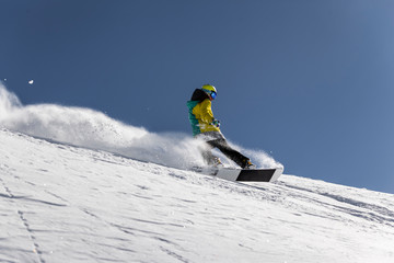 Snowboarder in green and yellow clothing enjoying winter vacation.