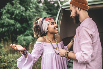 Smiling hippie man and woman stay near retro van