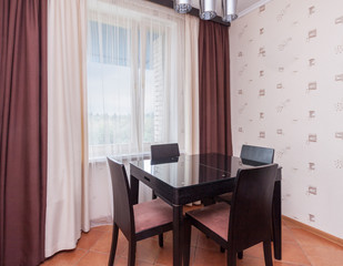 Close up view of interior design modern dining room. Clean new house with one table and four chairs near to the window curtains cold winter day.