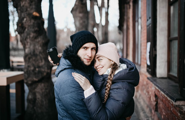 Loving couple in winter clothes and knitted hats walk around the city in the winter before Christmas and New Year.