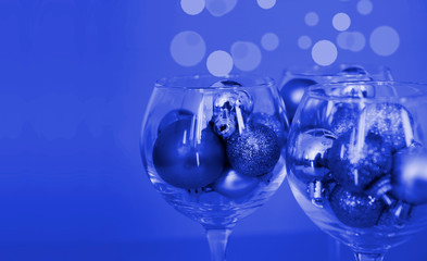 Glasses are filled with Christmas toys - concept photo of a festive New Year party, color classic Pantone 2020 blue