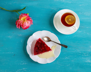 Dessert a piece of raspberry cake on a plate with a cup of tea on a bright background. . Aerial view.