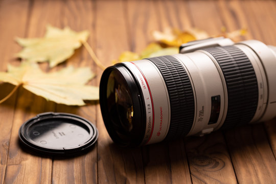 camera lens on wood background with autumn fall leaves