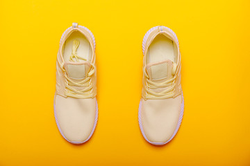 Sport shoes theme in yellow color. Pair of yellow sneakers on yellow background. Trendy summer color.