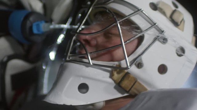 Close up shot of middle-aged male ice hockey player in helmet refreshing after match and pouring water on face