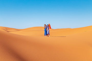 Fototapeta na wymiar Two girls in headscarves in the Sahara desert.