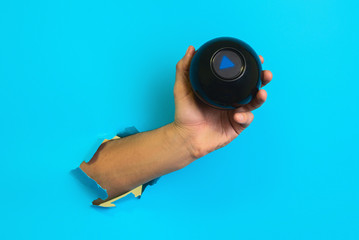 Magic ball with prediction in hand on blue background. hand breaks paper