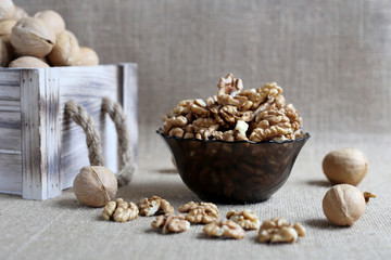 Peeled walnuts poured into bowl , standing on table covered with burlap. Near still nuts