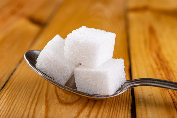 White sugar cubes. Sweetener for kitchen dishes on a wooden table.