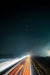Blurry long exposure light trails of cars driving on a autobahn motorway on a night dark winter day. 