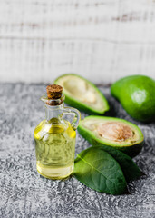 Avocado oil in a bottle and fresh avocado with leaf