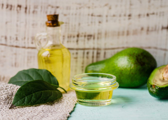 Avocado oil in a bottle and fresh avocado with leaf