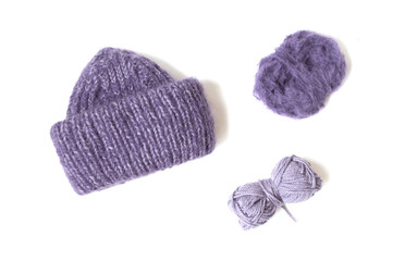 Purple hat and yarn balls on the white background. Knitted clothes. 