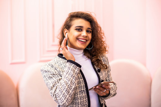 Young Pretty Woman Use Airpods Use Phone Standing In Cafe