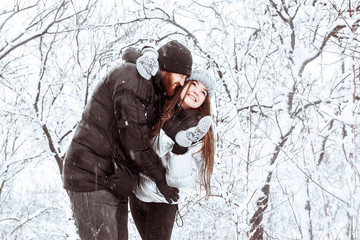 Happy winter holidays. Romantic young couple. Snowy winter day. Christmas and holidays concept - happy couple having fun over winter forest background