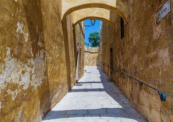 Narrow street with limestone walls in the Cittadella of Victoria in Gozo, Malta.