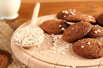Oatmeal in a spoon, next to milk and oatmeal cookies.