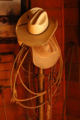 Old cowboy hats and rope on a hat stand
