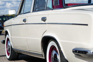vintage car. beige retro car. on the chrome details a sunny highlight. rear side view. sun against...