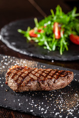 Farm organic food concept. Grilled beef steak with grill. Fried steak on on black slate, on a black background.