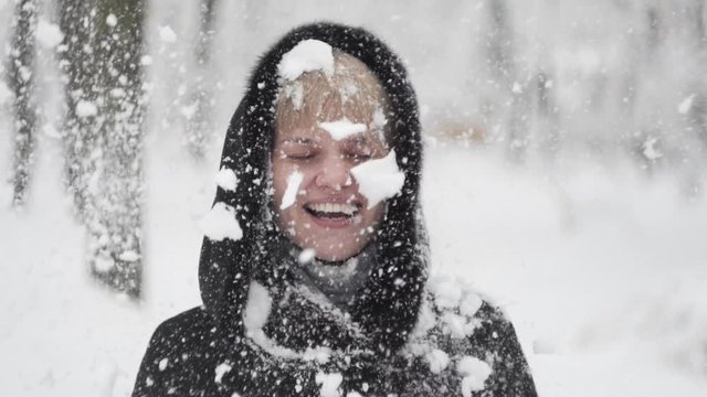 Portrait of a happy young woman in the middle of a snowball fight getting a snowball in her face.