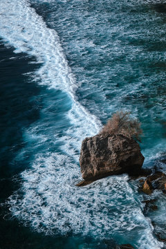 Aerial view to ocean waves with rocks. Blue water background. Bali, Indonesia.