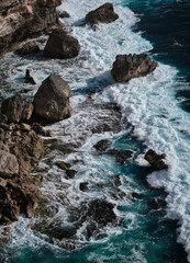 Aerial view to ocean waves with rocks. Blue water background. Bali, Indonesia.