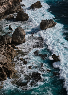 Aerial view to ocean waves with rocks. Blue water background. Bali, Indonesia.