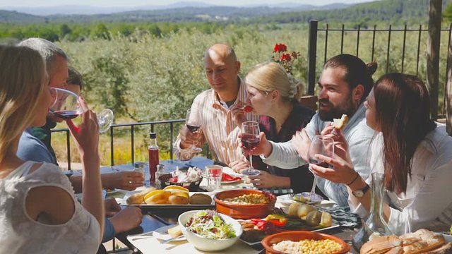 Positive middle class people enjoying food and wine on the open-air terrace