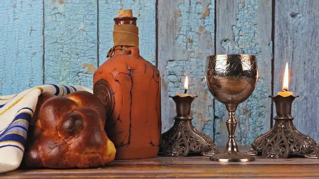 Shabbat Jewish holiday with challah bread on a candles and cup of wine.