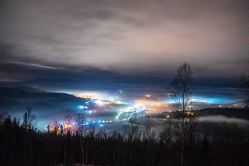 Night city in the fog in the mountains in autumn