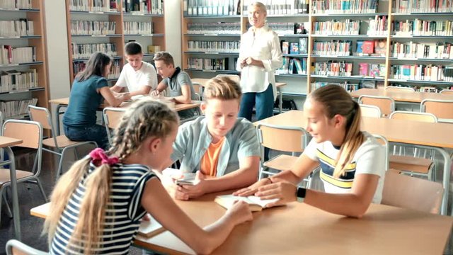 Teenage students working in groups in college library