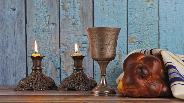 Shabbat eve table with covered challah bread, candles and cup of wine.