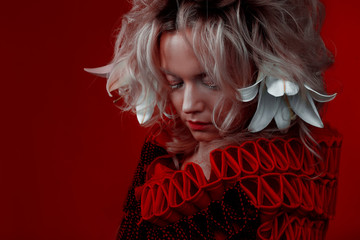 Shades of red. Strange attractive woman in a red outfit, on a red background, with lily flowers in...