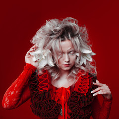 Shades of red. Attractive woman, in a red dress, posing on a red background, with white lily...
