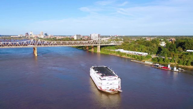 Good aerial over a Mississippi River paddlewheel steamship going under three steel bridges near Memphis, Tennessee.