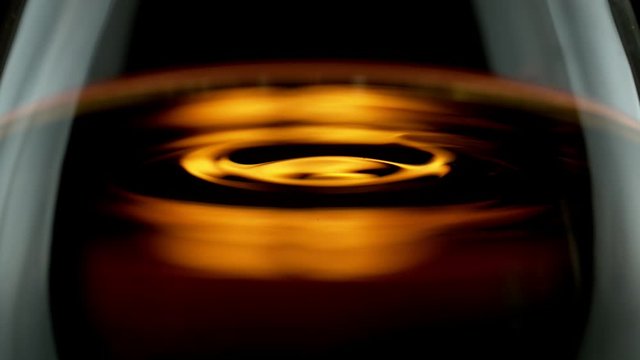 Super slow motion of waving whiskey, cognac or rum in macro shot. Filmed on high speed cinema camera, 1000 fps